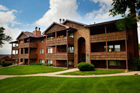 an apartment building with a green lawn and a blue sky