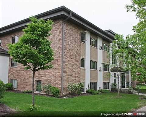 a brick apartment building with a tree in the yard