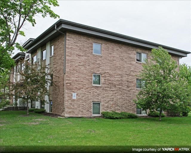 a brick building with green grass and trees