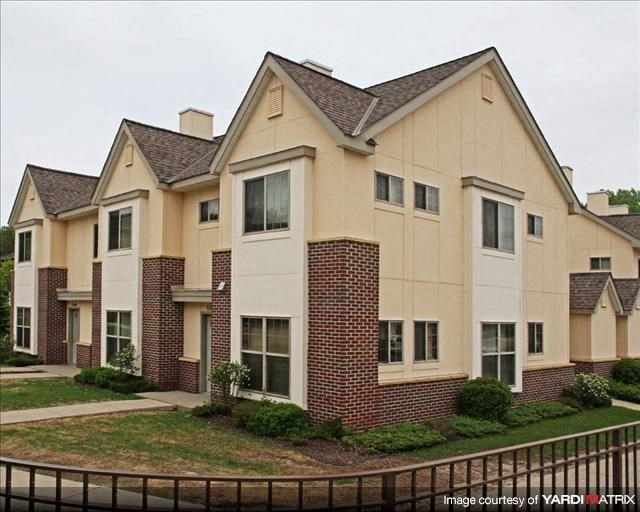 an apartment building with a yard and a fence