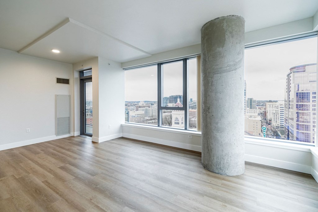 an empty living room with a large window and a city view