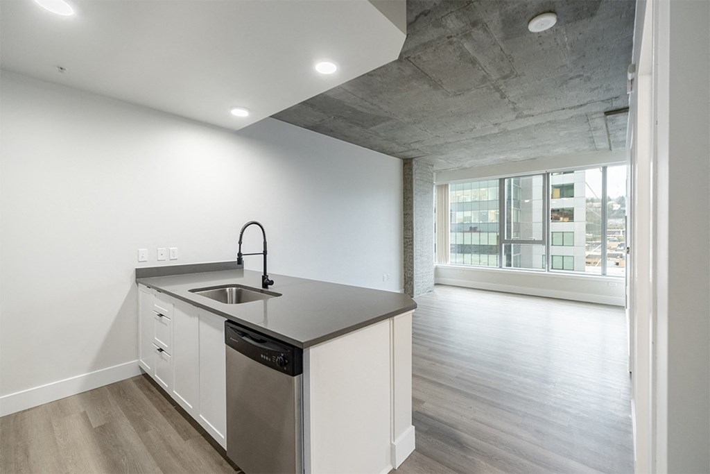 a kitchen with a sink and a counter top in a room with a large window