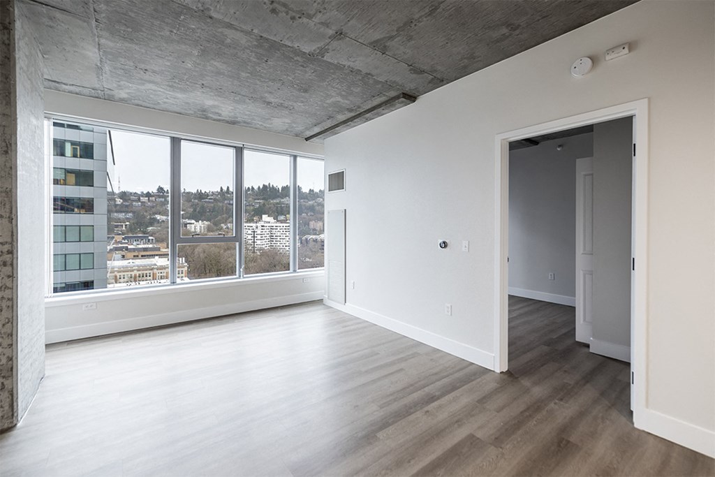an empty living room with a large window and wooden floors