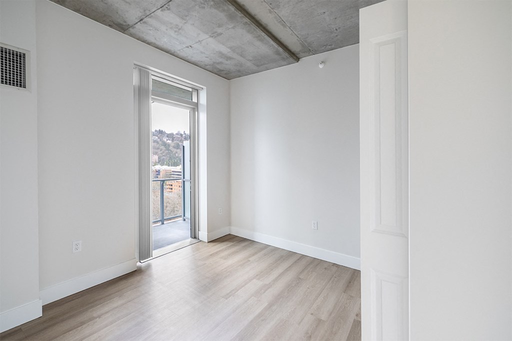an empty living room with a door to a balcony