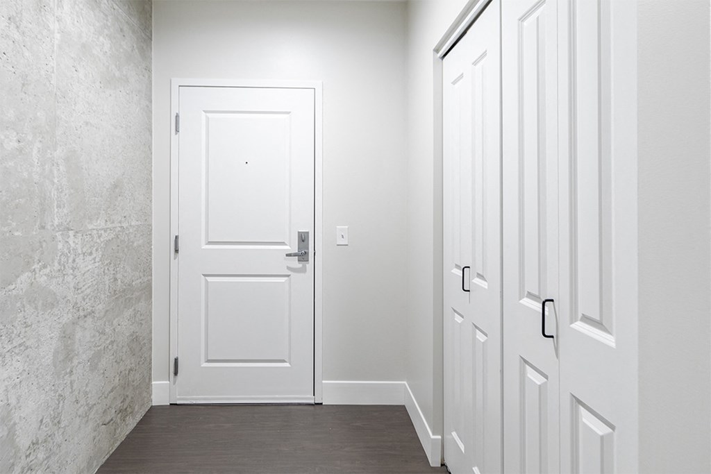 a hallway with white doors and white walls and a wood floor