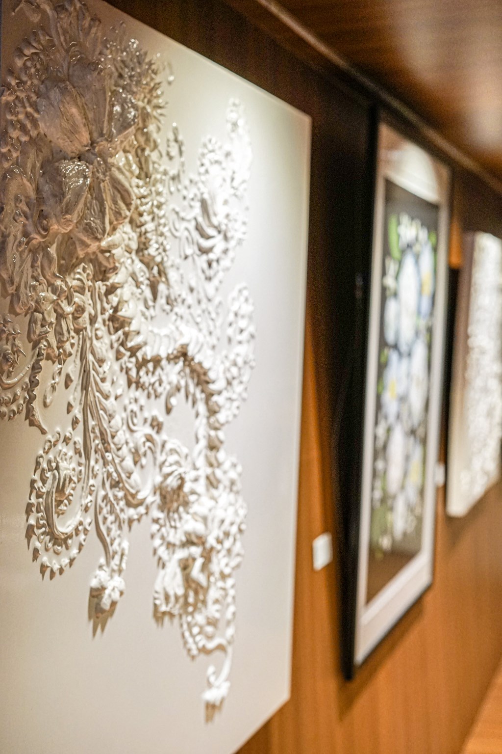 a painting on a wall in a room with other paintings and a window