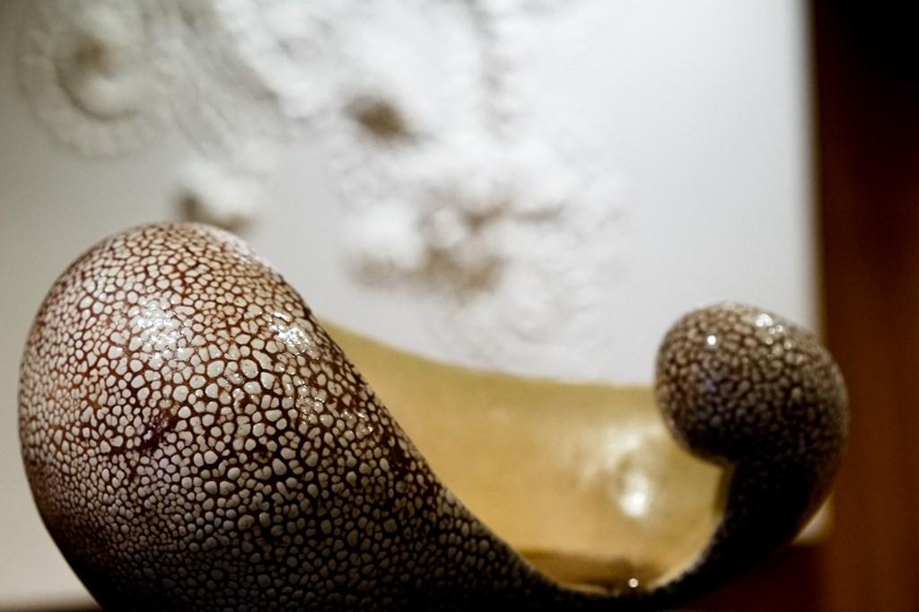 a close up of a bird sculpture with a painting in the background