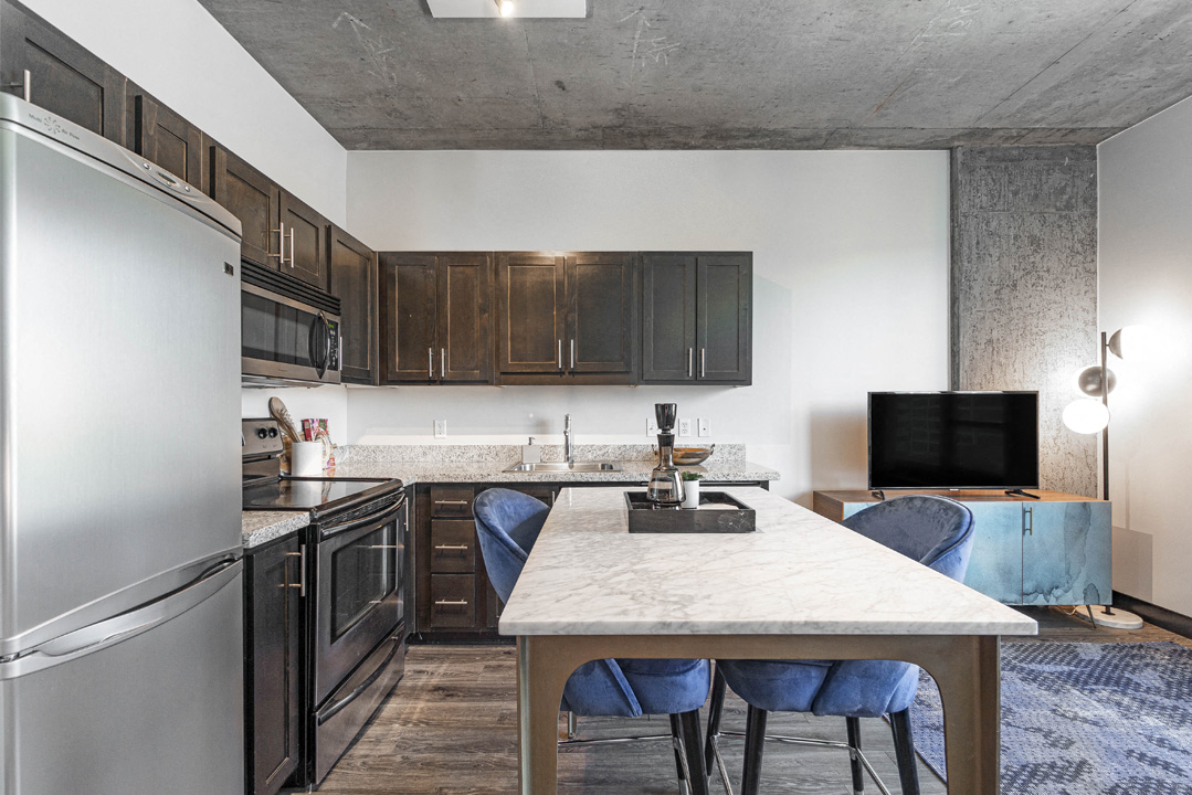 a kitchen with stainless steel appliances and a table with blue chairs