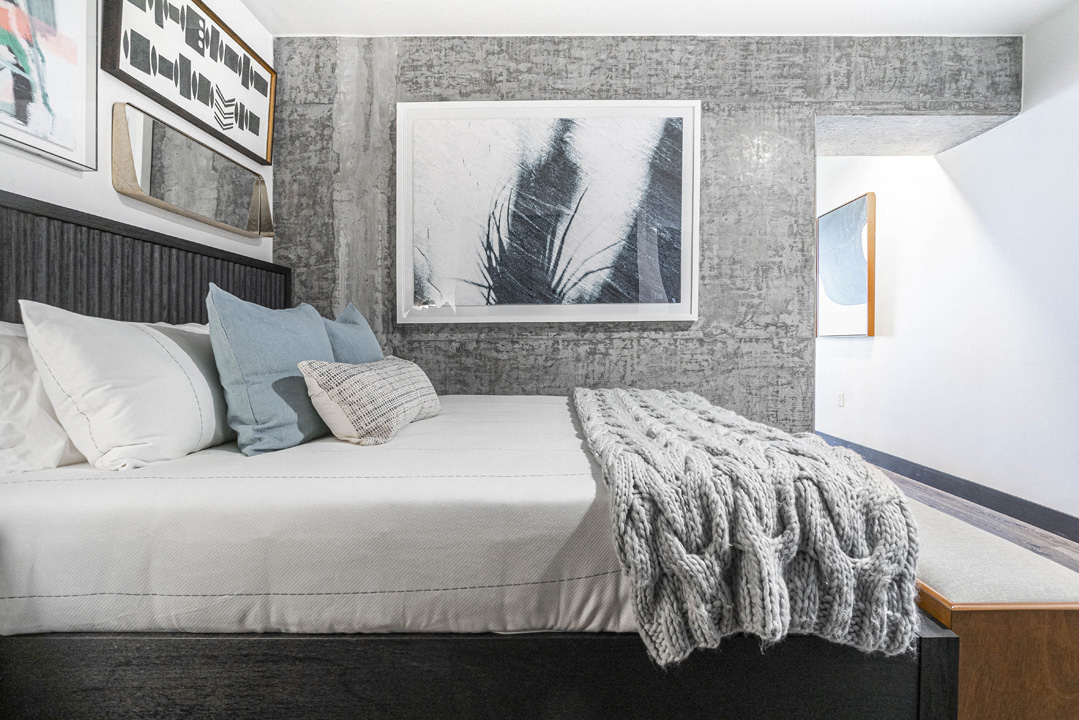 a bedroom with a bed with pillows and a blanket and a wall with pictures