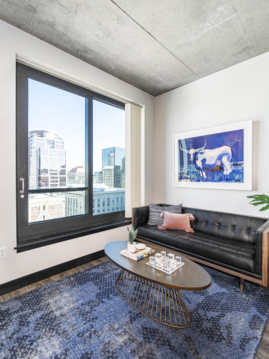 a living room with a black leather couch and a coffee table and a large window