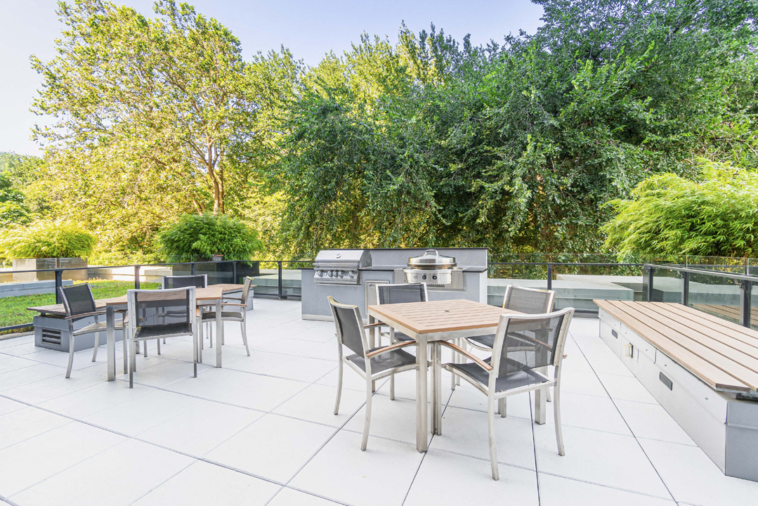 the patio of a home with tables and chairs and a grill