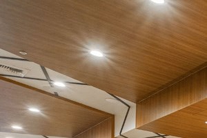 a large gray bench sits in the middle of a wood paneled lobby