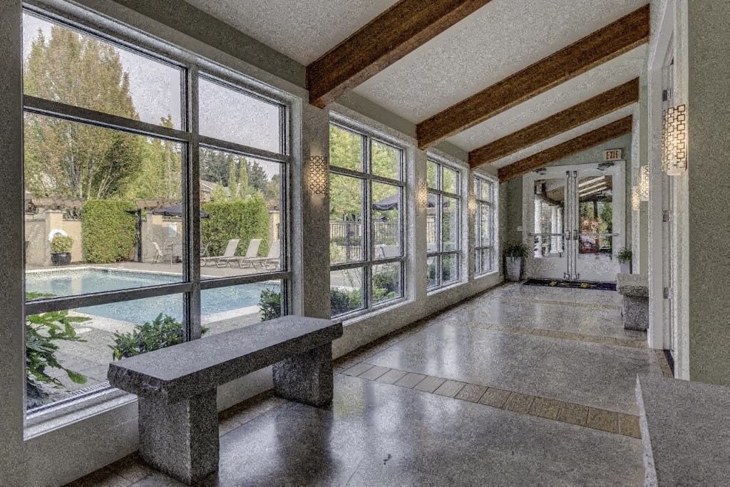 a long hallway with large windows and a bench