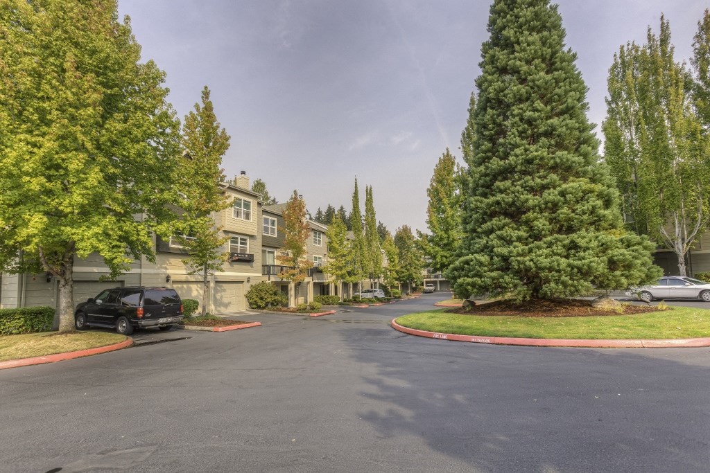 the view of a street with cars parked in front of apartment buildings