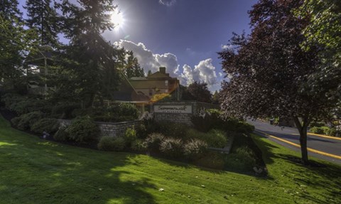 a view of a building on a lawn with trees and bushes