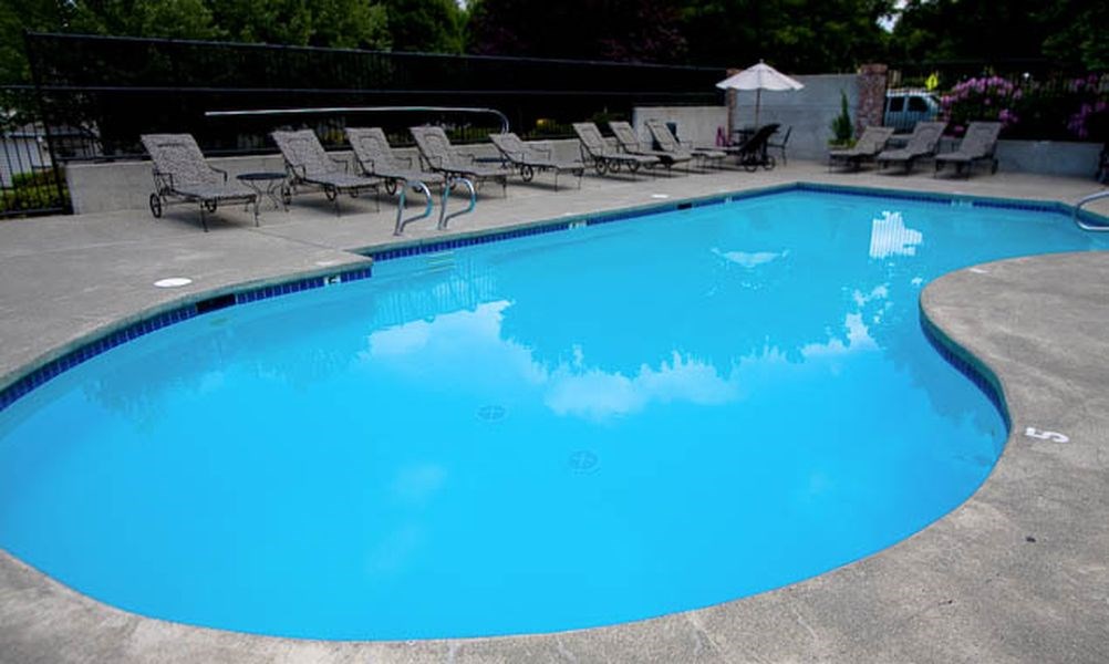 a large blue swimming pool with chairs and umbrellas
