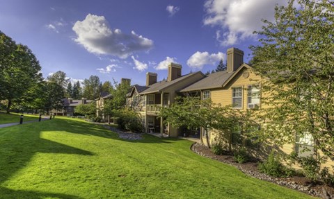 a row of houses on a green lawn with trees