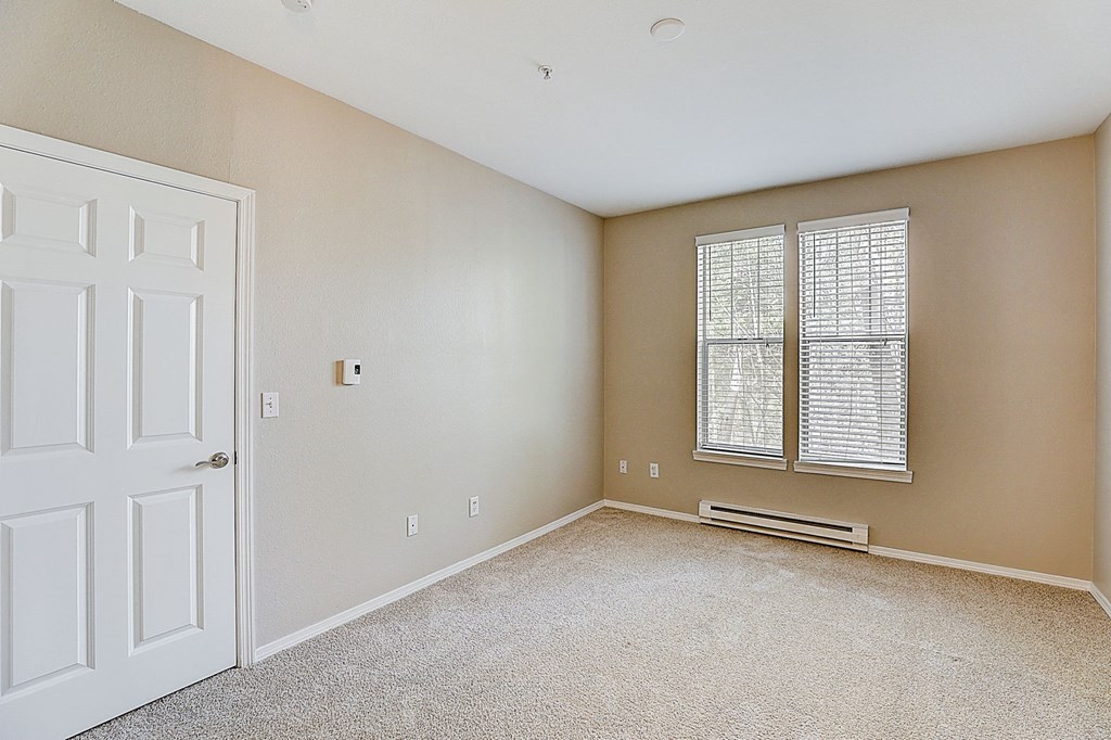 an empty room with a white door and a window