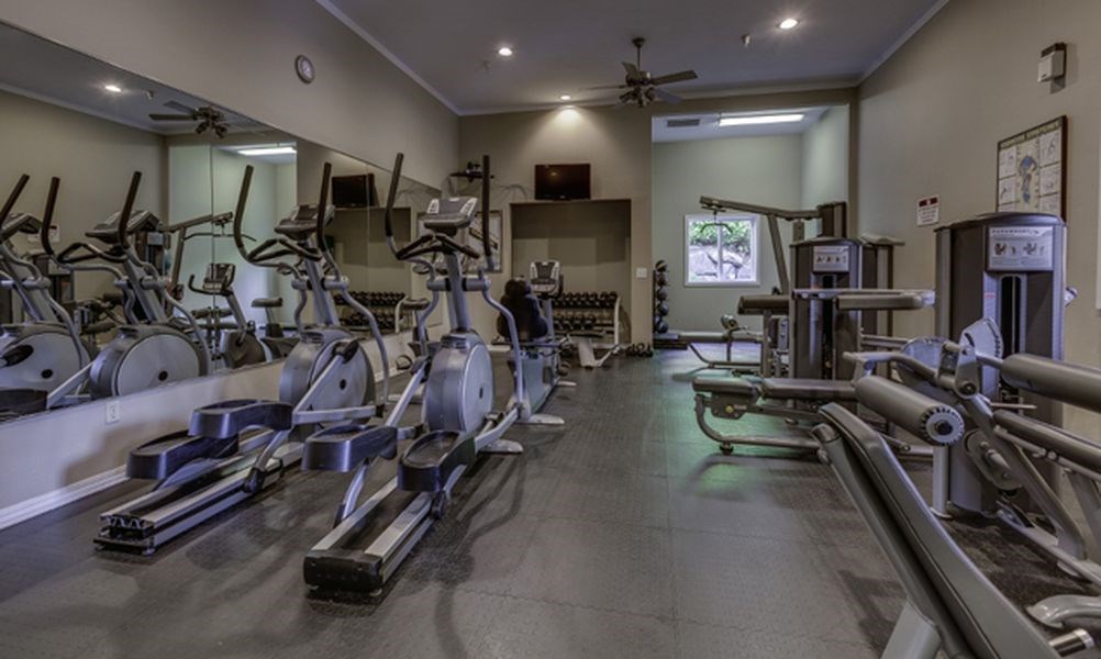 a gym with cardio equipment and weights on the floor