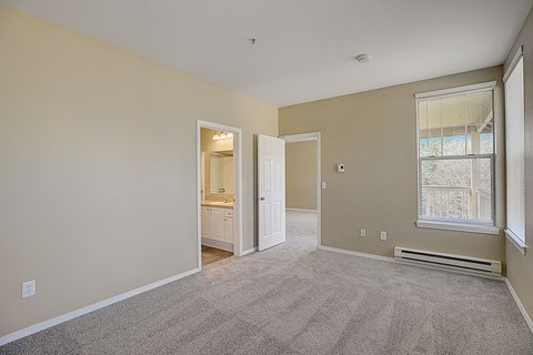 an empty living room with carpet and a door to a bathroom