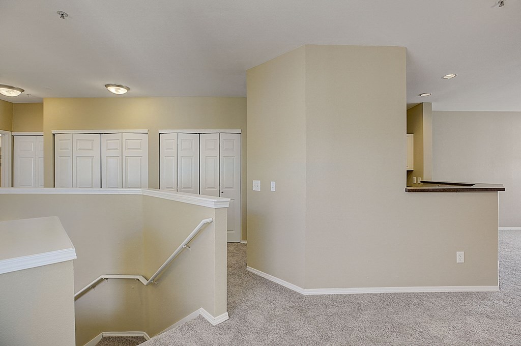 an empty living room with white cabinets and a staircase