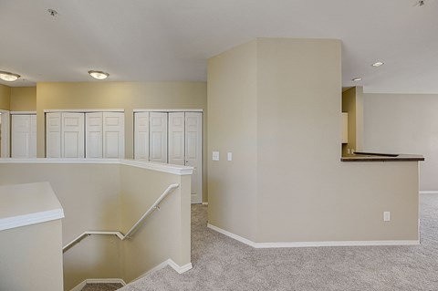 an empty living room with white cabinets and a staircase