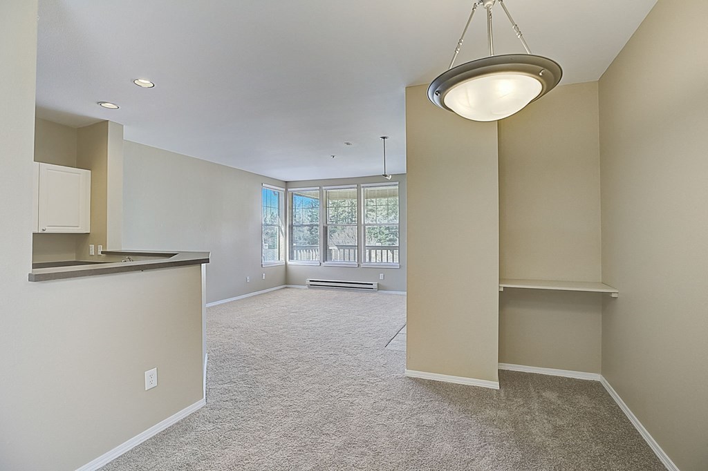 an empty living room and kitchen with a large window