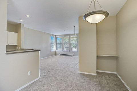 an empty living room and kitchen with a large window