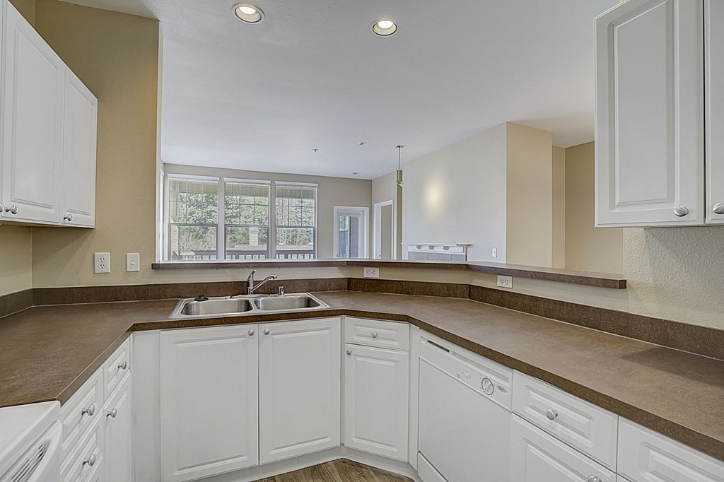 a kitchen with white cabinets and counters and a sink