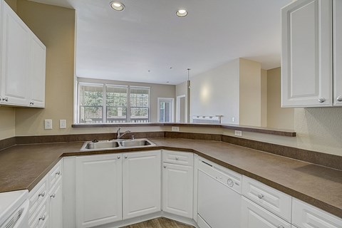 a kitchen with white cabinets and counters and a sink