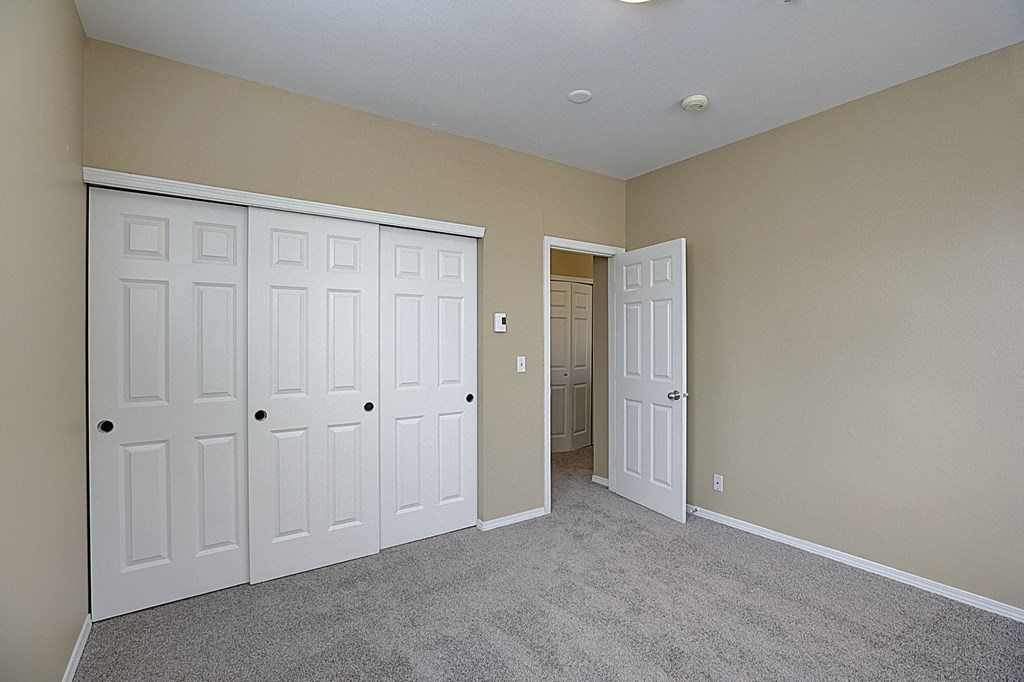 an empty bedroom with three closets and two doors