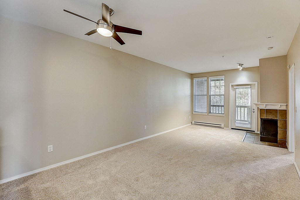 an empty living room with a ceiling fan and a fireplace