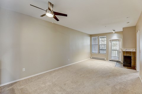 an empty living room with a ceiling fan and a fireplace