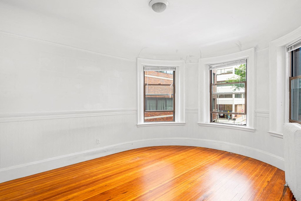 a living room with a hard wood floor and three windows