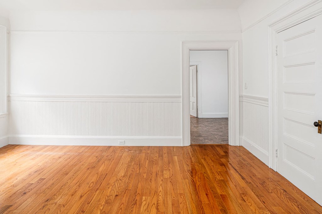 an empty room with wood floors and white walls