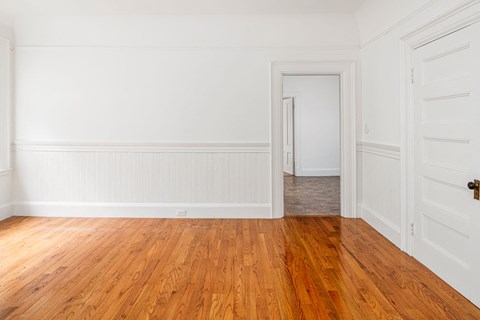 an empty room with wood floors and white walls