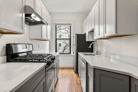 a kitchen with white cabinets and black appliances and a window