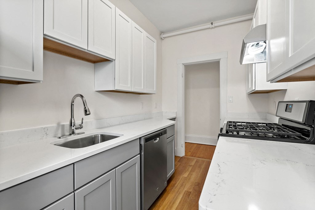 a kitchen with white cabinets and a sink and a stove