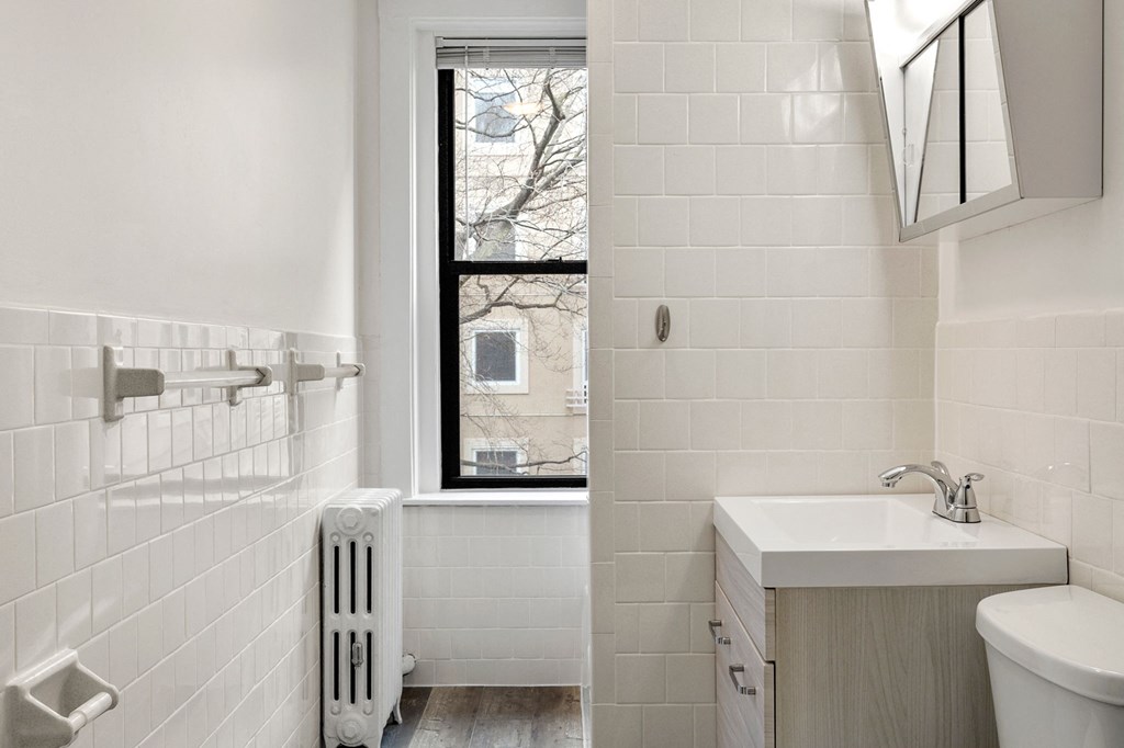a white bathroom with a window and a sink and a toilet