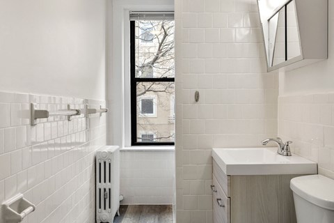 a white bathroom with a window and a sink and a toilet