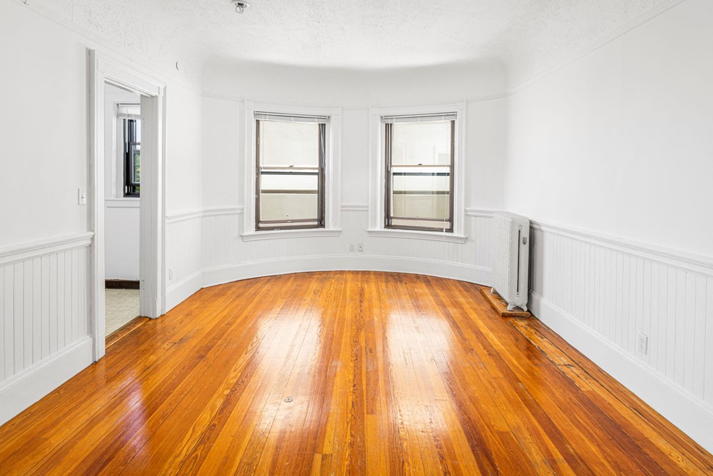 an empty living room with wood floors and windows