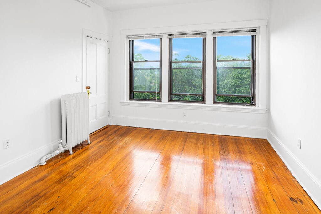 an empty room with wood floors and three windows
