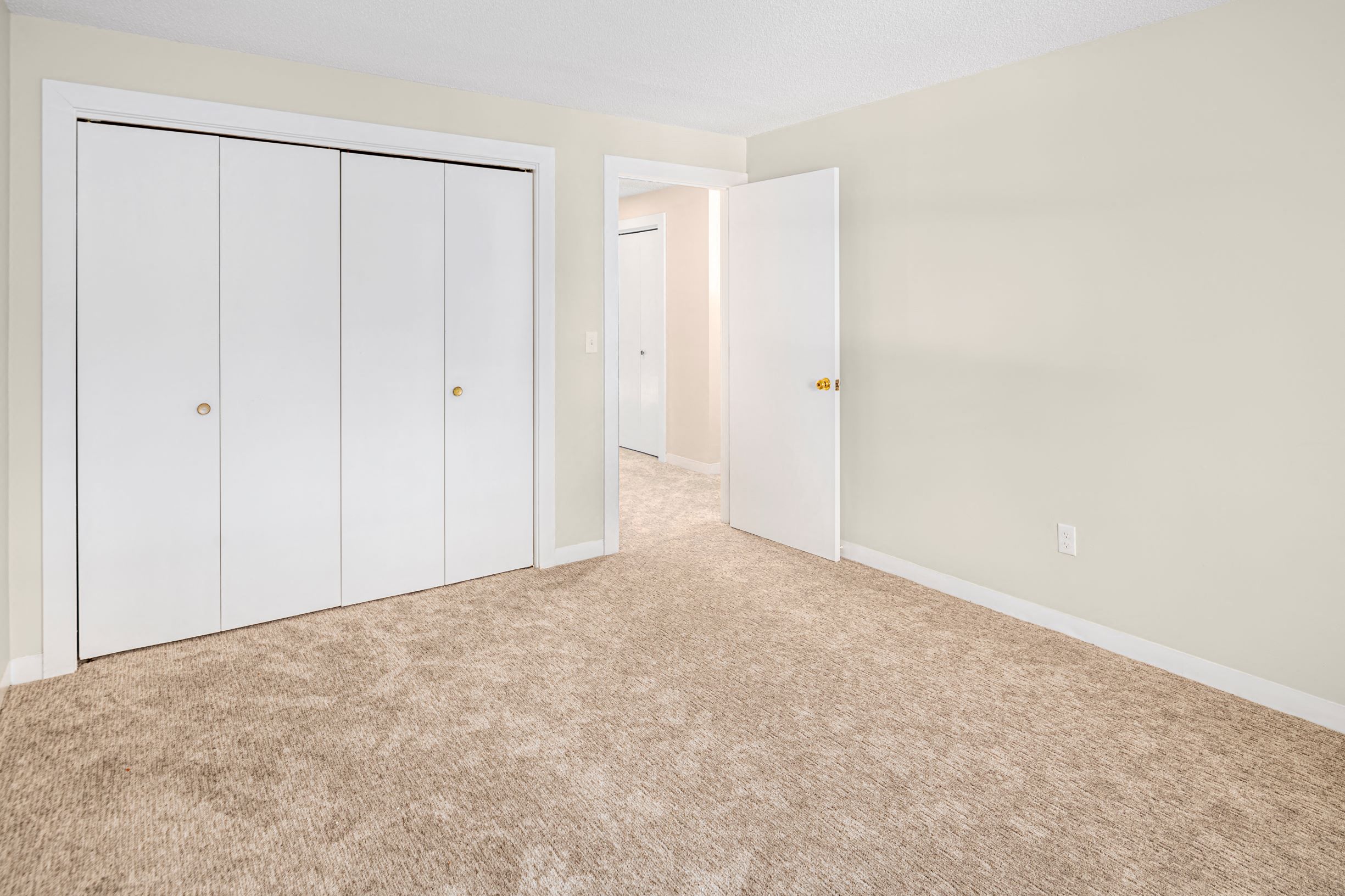 an empty bedroom with closet doors and carpet