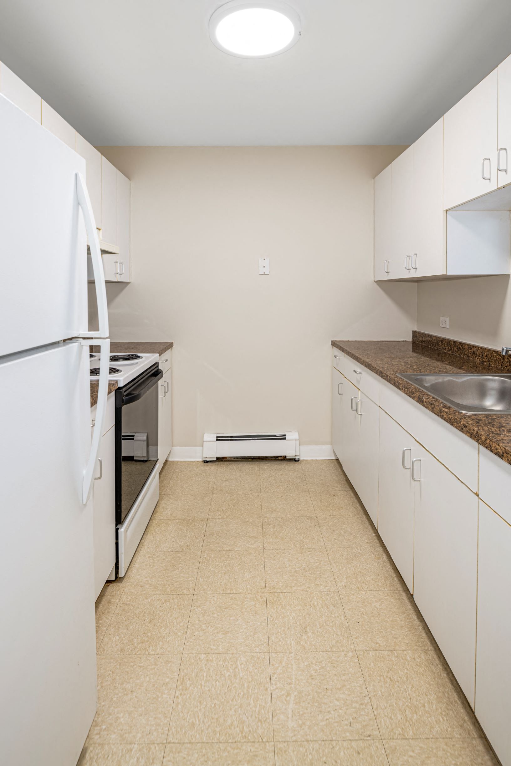a kitchen with white cabinets and appliances and a tiled floor
