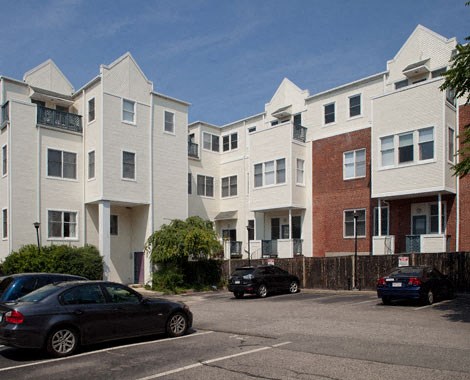 a row of apartment buildings with cars parked in a parking lot