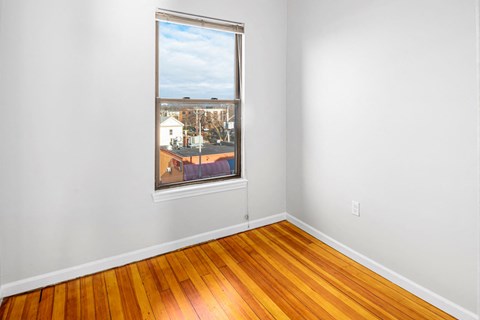 a bedroom with a large window and wooden floors