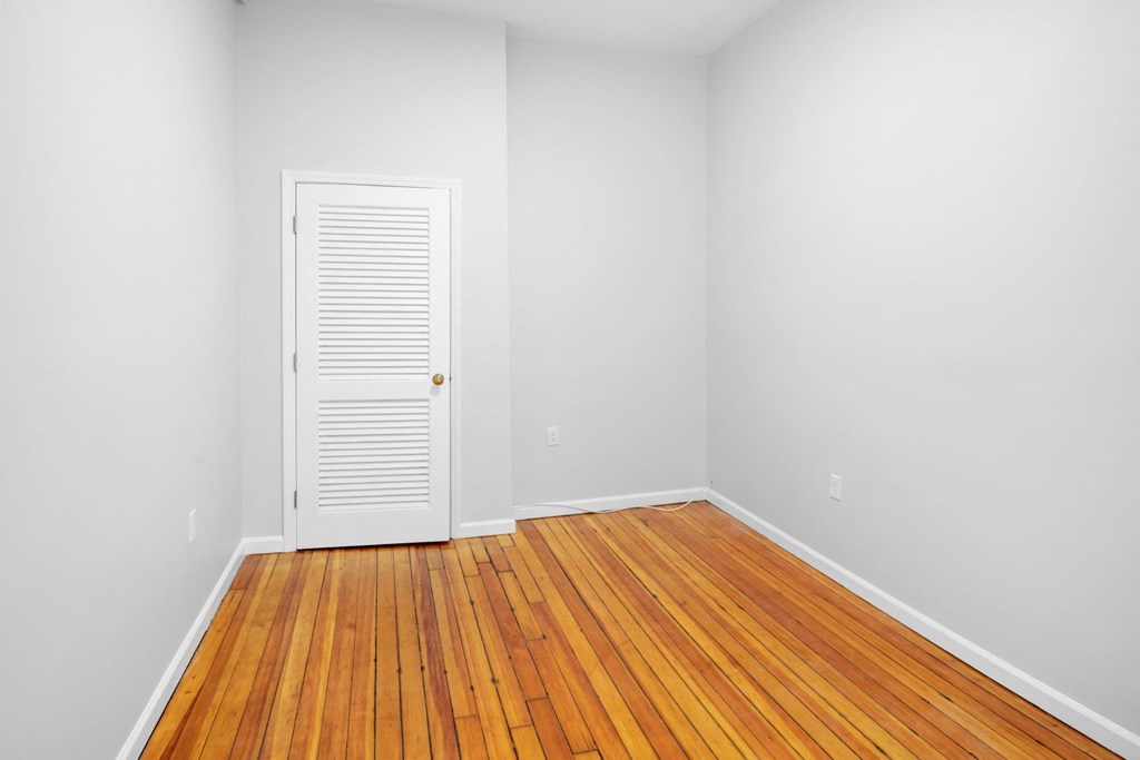 room with wood floor and white walls and an open door