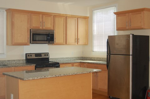 a kitchen with wood cabinets and granite counter tops and a refrigerator