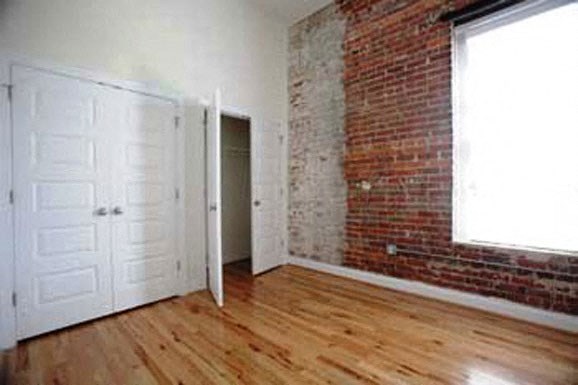 an empty room with a brick wall and wooden floors