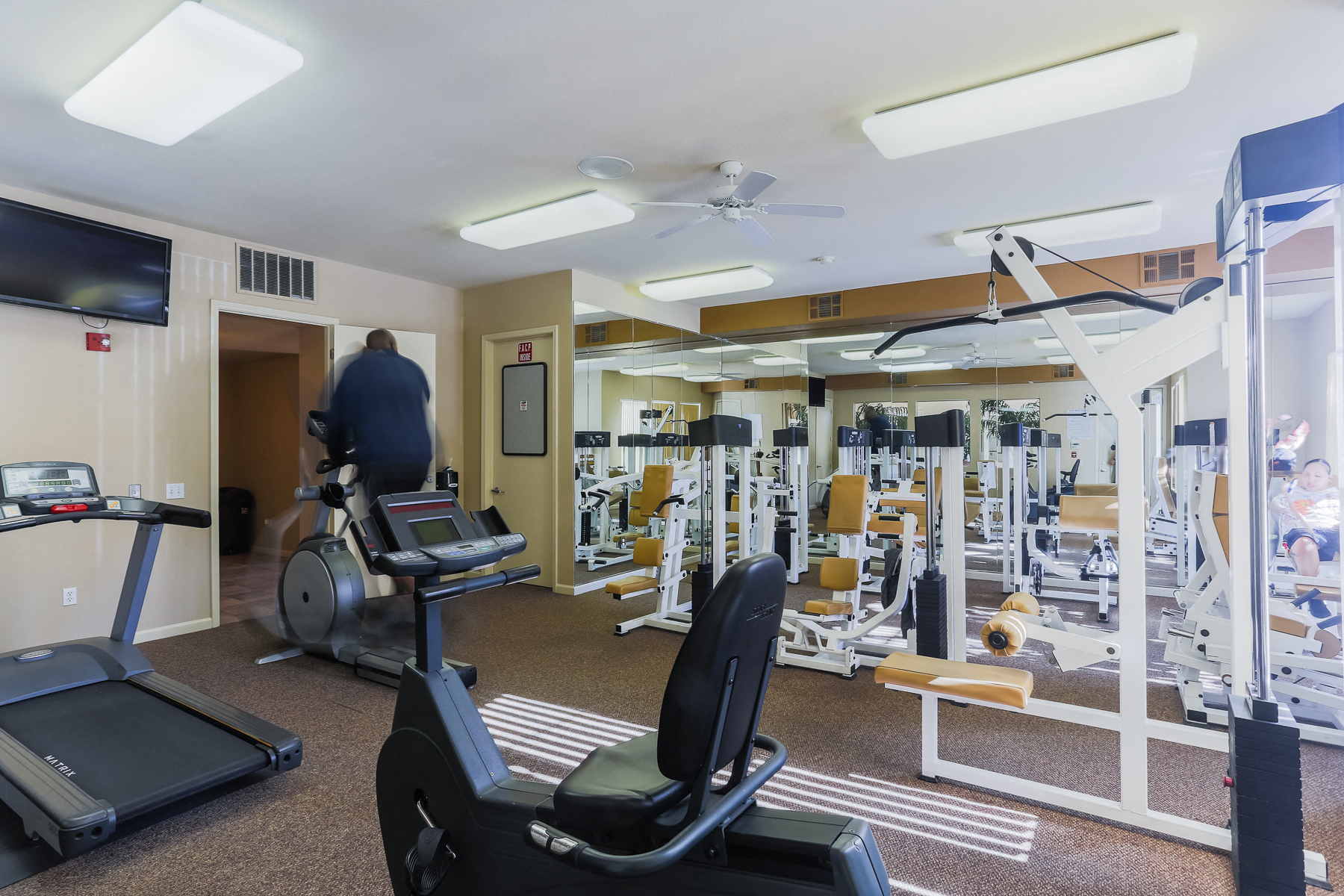 a gym with a lot of exercise equipment and a tv